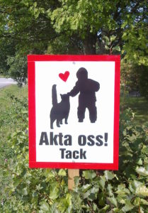 liikennemerkki jossa kissa, lapsi ja teksti "Akta oss, tack"